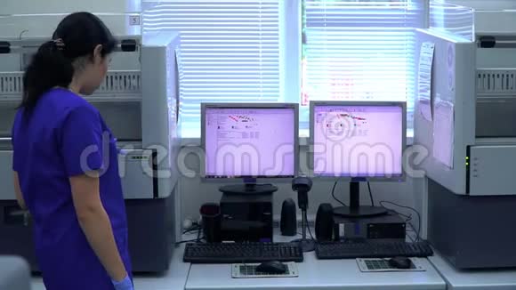 两名穿着蓝色制服的专业女性实验室工作人员在电脑前讨论研究视频的预览图