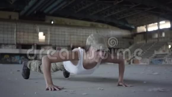 穿着军装的年轻女子从一栋废弃建筑的混凝土地板上扭动身体女人训练视频的预览图