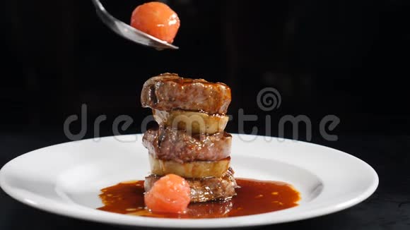 慢动作食物视频概念牛肉奖章漂亮地把一个放在另一个上面在白色的盘子里倒入美味的酱汁视频的预览图