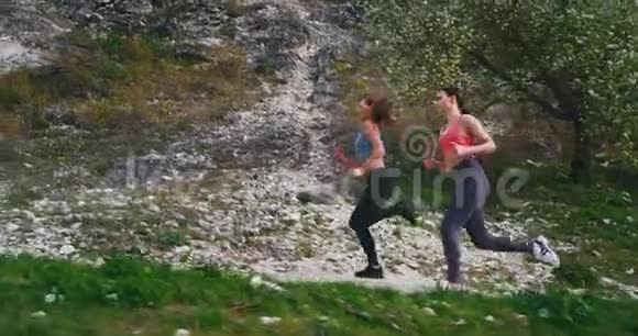 美丽的两位女士在风景优美的山路中间穿着运动服辛苦地锻炼了一天视频的预览图