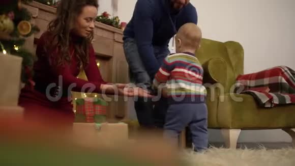 可爱快乐快乐的妈妈爸爸和宝宝在家里的圣诞树旁边度过他们的闲暇时光视频的预览图