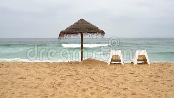 暴风雨中两把扶手椅和一把草伞在海边视频的预览图