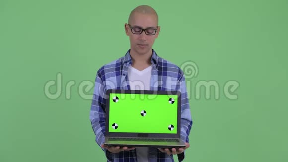 穿着秃头的时髦男人展示笔记本电脑视频的预览图