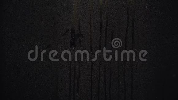 水滴的特写在夜晚落在黑暗的玻璃上概念雨天视频的预览图