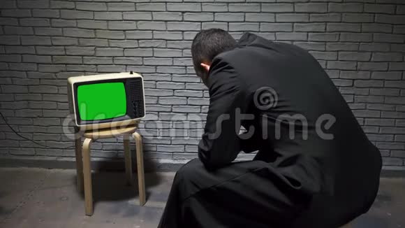 穿外套的男人看复古电视的视频视频的预览图