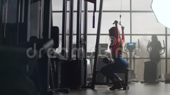 早上在健身房锻炼身体在有大窗户的房间里训练一个女人使用椭球视频的预览图