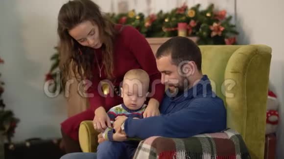 妈妈爸爸和小宝宝都在房间里装饰着圣诞节男人抱着小儿子女人视频的预览图