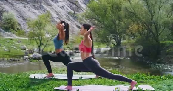 两位女士一起在大自然中练习瑜伽她们在瑜伽垫上做伸展身体的运动视频的预览图