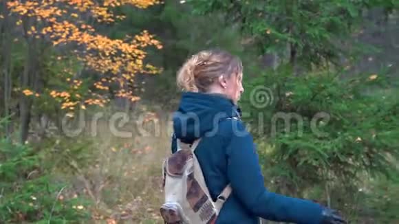 一个身材苗条的漂亮女人背着一个背包手里拿着干草叶走过秋天视频的预览图