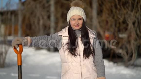 小女孩拿着铲子站在后院雪下后准备清雪的女人视频的预览图