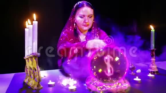 一个吉普赛女人在一个魔法沙龙里烟雾缭绕在水晶球上猜测里面出现了一个美元的标志视频的预览图