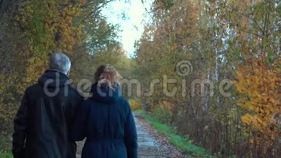一个身材苗条头发花白的男人戴着眼镜一个身材苗条漂亮中年的女人走在秋天公园大道的下面视频的预览图