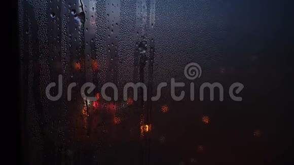 晚上雨滴落在玻璃上的特写和透过窗户模糊的光点概念视频的预览图