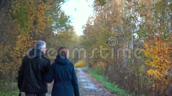 一个身材苗条头发花白的男人戴着眼镜一个身材苗条漂亮中年的女人走在秋天公园大道的下面视频的预览图