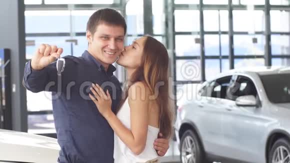 快乐的白种人夫妇拥抱在新车前拿着钥匙在汽车经销商视频的预览图