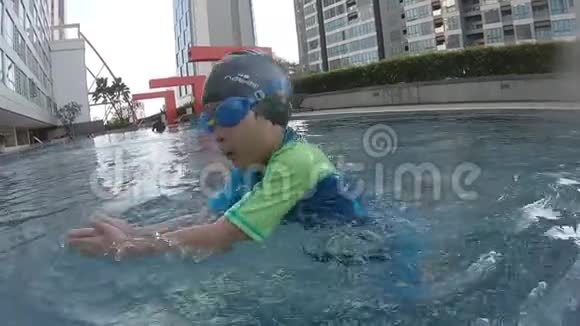 小男孩穿着蓝色泳衣在游泳池里游泳视频的预览图