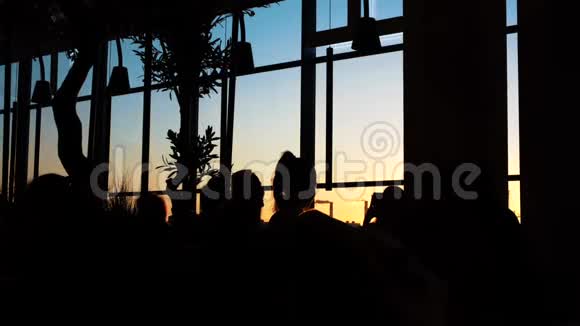 日落时分站在靠近窗户的黑暗房间里的人剪影概念夜间观察视频的预览图