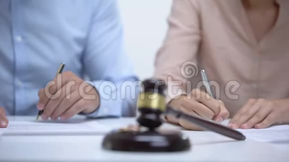 结婚戒指和木槌特写配偶在后台签署离婚文件视频的预览图