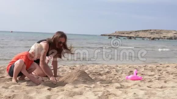 一家人站在海边的海滩上的沙堡视频的预览图