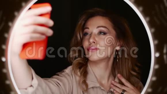 女化妆师拿着智能手机在环光面前自拍视频的预览图