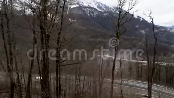 在位于山区的弯曲道路上行驶的汽车的鸟瞰图库存录像飞越深秋的森林和雪视频的预览图