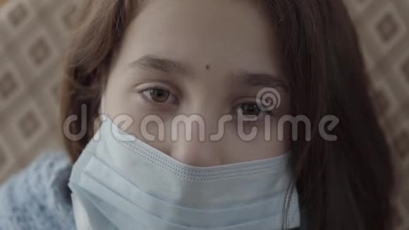 闭上脸悲伤的生病的女孩她的脸上戴着无菌面具看着镜头特写女孩有传染性视频的预览图