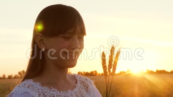小女孩手里拿着小麦在夕阳的照耀下微笑视频的预览图