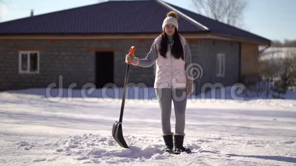 小女孩拿着铲子站在后院下完雪后准备清雪的女人视频的预览图