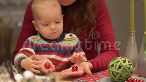 可爱的年轻母亲和婴儿在现代厨房里玩得很开心妈妈和孩子玩旋转着圆圆的糖果幸福家庭视频的预览图