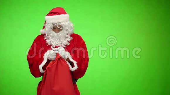 圣诞老人带着礼物看着袋子摸了摸头色度键视频的预览图