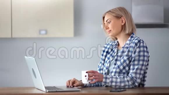 可爱的自由职业者用笔记本电脑在家工作和喝咖啡打字视频的预览图