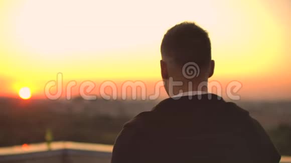 从后面看日落时一个人走在屋顶上喝着啤酒看着城市的美丽景色视频的预览图