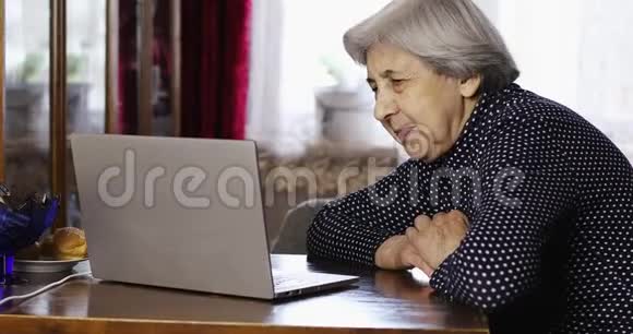 老太太用笔记本电脑通过视频通话与孙女交谈视频的预览图