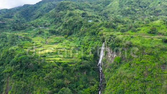 山脉覆盖着丛林和远处的瀑布鸟瞰视频的预览图