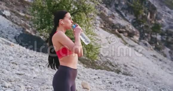 在山地运动中一位运动的女士在经过艰苦的锻炼后非常口渴喝了一些水还在跑步视频的预览图