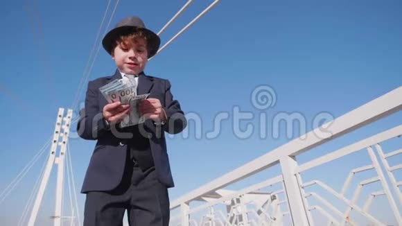 无忧无虑的小男孩从桥低角度扔现金小男孩看起来像商人浪费金钱视频的预览图