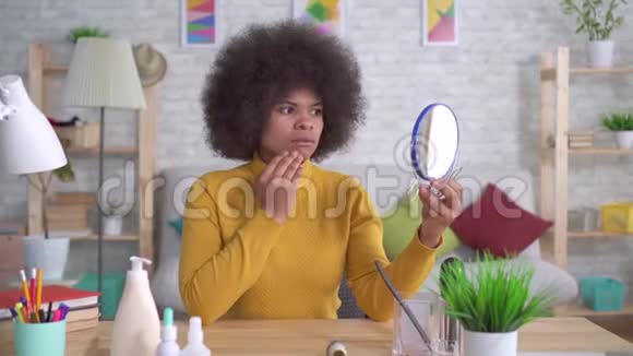 美国黑人妇女的肖像她的发型是非洲式的地照镜子发现皮肤有缺陷视频的预览图