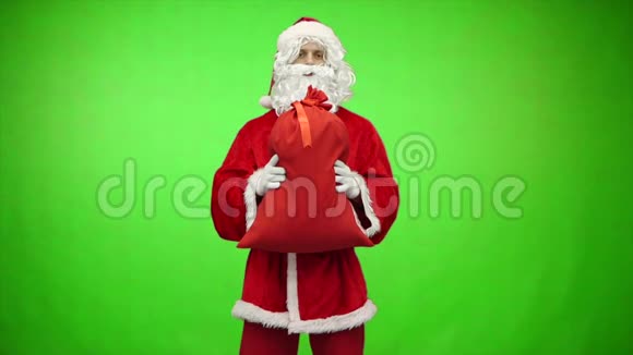 圣诞老人在绿色背景上赠送带有礼物的袋子慢动作视频的预览图