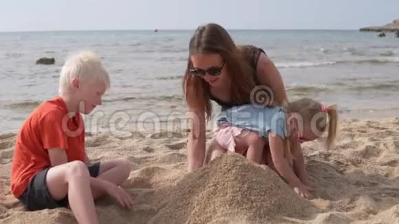 母亲带着孩子在海滩上建了一座沙堡视频的预览图