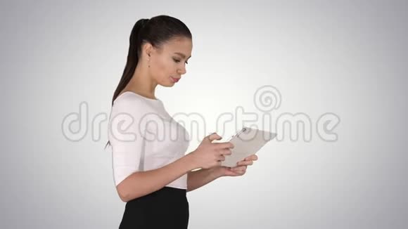 美丽的年轻成年女人在梯度背景下玩平板电脑游戏视频的预览图