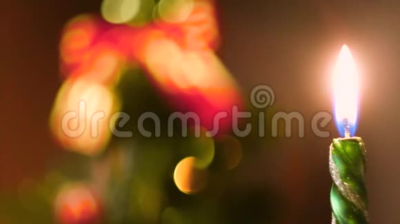 美丽的绿色蜡烛燃烧在平安夜与装饰模糊的圣诞树的背景概念视频的预览图