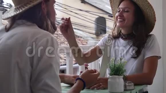 可爱的一对戴着草帽的夫妇坐在咖啡馆里互相喂冰淇淋视频的预览图