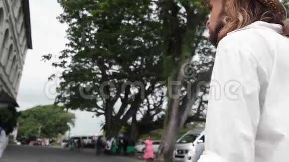 穿着草帽和白衬衫的年轻帅哥在街上走着视频的预览图