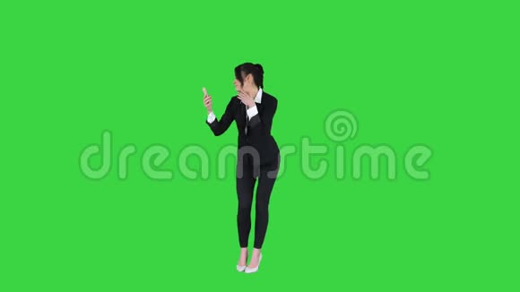 商务女性在绿色屏幕上观看智能手机的预演和舞蹈色度键视频的预览图