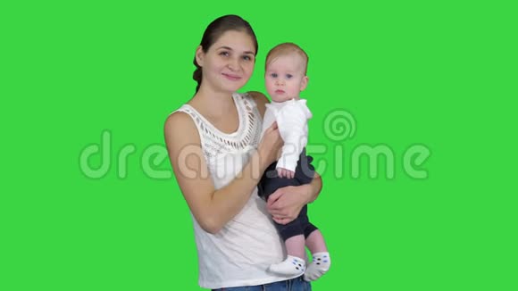 可爱的小男孩在妈妈的手中寻找绿色屏幕上的相机色度键视频的预览图