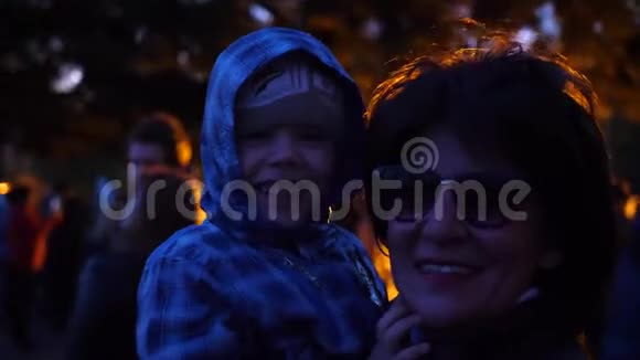 晚上家人在海滨公园散步明亮的灯光祖母把孩子抱在怀里视频的预览图