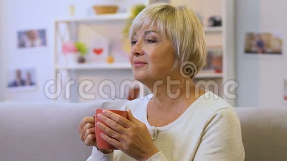 中年妇女喝着舒缓草药的热茶恢复水的平衡视频的预览图