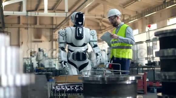 在工厂的平板电脑上打字时男人会检查机器人的移动情况视频的预览图
