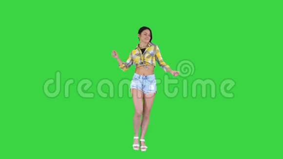 女孩穿着方形衬衫和牛仔裤短裤运动鞋在绿色屏幕上跳舞铬钥匙视频的预览图