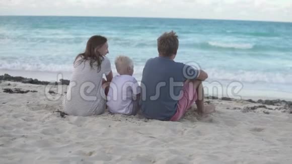 一家人坐在海滩上看着大海视频的预览图